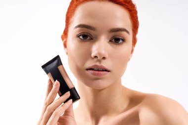 Çarpıcı kızıl saçlı güzel bir kadın, zarafet ve tarz saçan bir güzellik ürününü ön plana çıkarıyor..