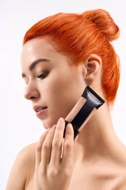 Çekici genç kadın makyaj yapıyor. Güzelliğini ve moda anlayışını yumuşak ışıkta vurguluyor..