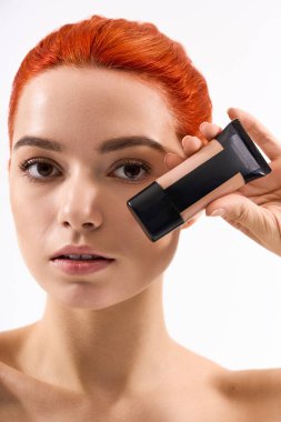 Güzel bir kadın en sevdiği makyaj ürününü tutarken göz alıcı bir ten ve tarz sergiliyor.