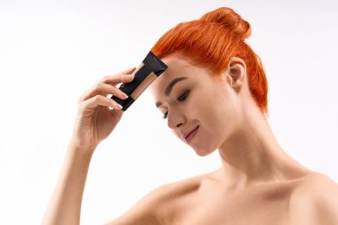 Turuncu saçları olan güzel bir kadın zarif bir şekilde gülümserken görünüşünü güzelleştirir..