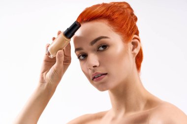 Genç bir kadın stil sahibi kızıl saçlarını sergilerken temellerini geliştirir..