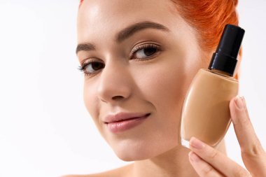 Güzel hatları olan genç bir kadın makyaj ürününü beyaz bir arkaplanda gururla sergiliyor..