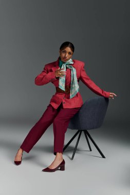 Şık bir genç kadın, çağdaş bir stüdyo ortamında rahat bir şekilde şık bir şekilde poz verir..