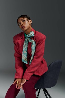 Genç bir Afrikalı Amerikalı kadın şık bir stüdyo içinde kendine güvenen bir şekilde poz veriyor..