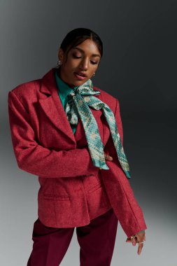 Tarz sahibi genç siyahi kadın, modern bir stüdyoda şık kıyafetlerini sergiliyor..