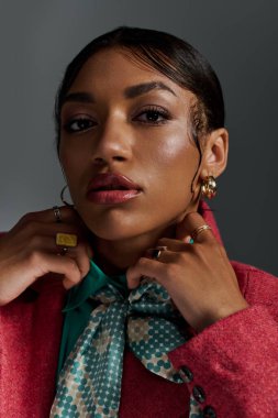 Genç bir Afrikalı Amerikalı kadın şık bir stüdyo içinde şık kıyafetler giyiyor..