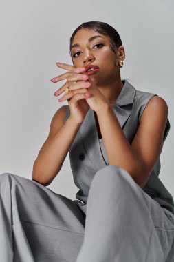 Kendine güveni tam genç bir kadın şık giyinmiş parlak bir stüdyoda zarif pozlar veriyor..