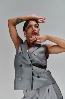 Genç bir Afrikalı Amerikalı kadın kendine güvenerek poz veriyor. Şık giyiniyor, zarafet saçıyor..