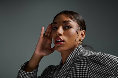 Genç bir Afrikalı Amerikalı kadın modern bir stüdyoda şık kıyafetler sergiliyor..