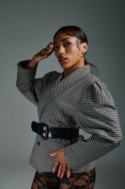 Genç bir kadın modaya uygun giyinip stüdyoda kendine has tarzını sergiliyor..