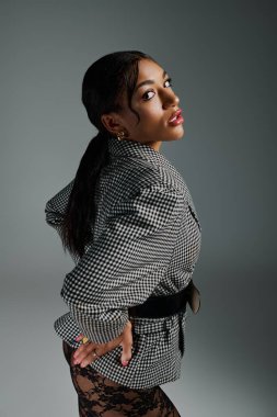 Genç kadın şık moda anlayışını gösterişli bir stüdyo ortamında sergiliyor..