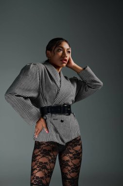 Genç bir Afrikalı Amerikalı kadın modern bir stüdyo ortamında şık ve moda kıyafetlerini sergiliyor..