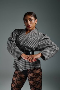 Genç bir Afrikalı Amerikalı kadın stüdyo arkaplanına karşı kendine güvenerek poz veriyor..