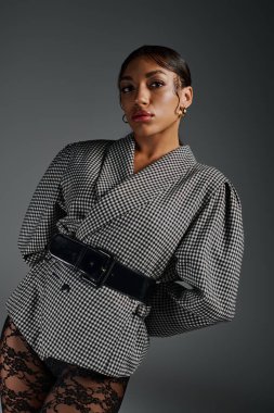 Genç Afro-Amerikan bir kadın zarif bir şekilde moda kıyafetle poz veriyor, kendine güveni tam..