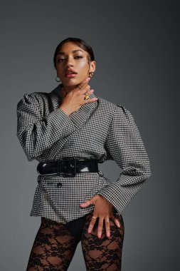 Şık giyinmiş kendine güvenen genç bir kadın stüdyoda kendine has moda anlayışını sergiliyor..