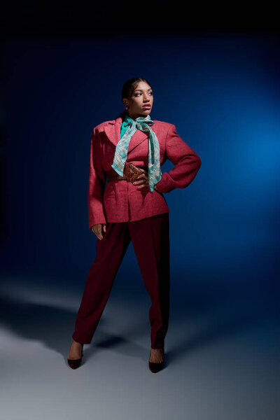 A young african american woman poses confidently in a vibrant studio wearing fashionable attire.