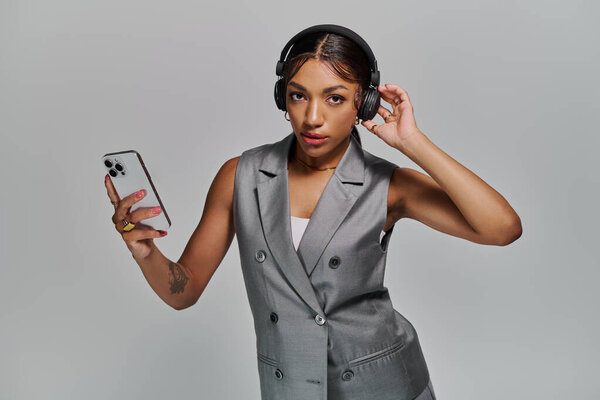 A young african american woman showcases her fashion sense while wearing stylish attire in a studio.