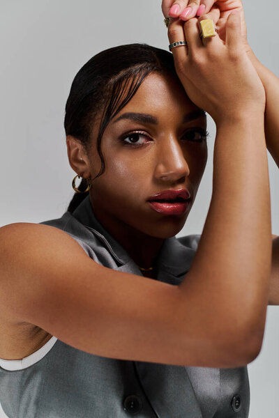 Стильная молодая афроамериканка уверенно позирует в студии, излучая модную элегантность.