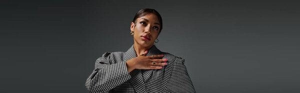 Уверенная в себе молодая женщина демонстрирует свой модный наряд в гладкой студийной обстановке с уравновешенностью, баннером