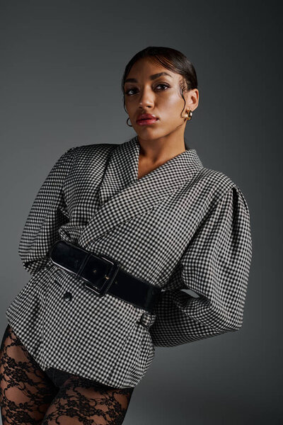 A young african american woman poses gracefully in a trendy outfit, exuding confidence.