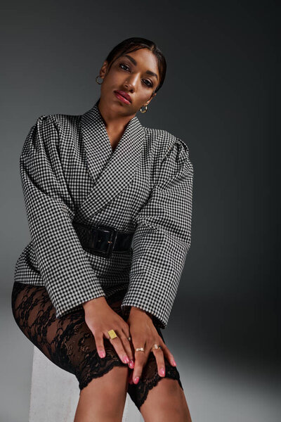 Молодая афроамериканка уверенно позирует в шикарном наряде в современной студии.