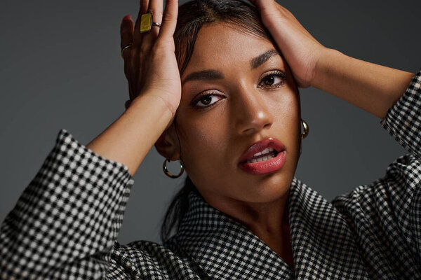 A young African American woman expresses confidence in smart casual attire within a studio space.