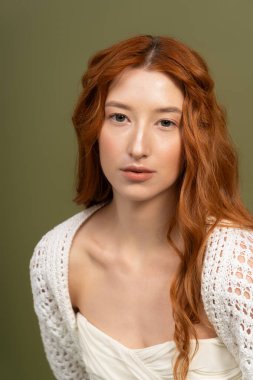 Kızıl saçlı genç bir kadın bir stüdyoda zarif poz veriyor, bahar modasını gösteriyor..