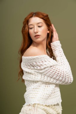 Güzel bir kızıl saçlı zarif bir şekilde stüdyoda poz veriyor, zarif bir bahar elbisesi sergiliyor..