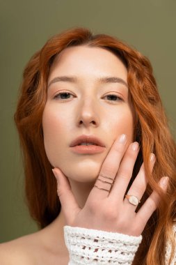 Kızıl saçlı genç bir kadın şık bahar kıyafetleri ve aksesuarları sergiliyor..