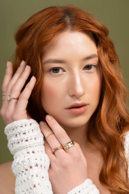 Çarpıcı kızıl saçlı genç bir kadın zarif poz verirken şık bahar kıyafetleri sergiliyor..