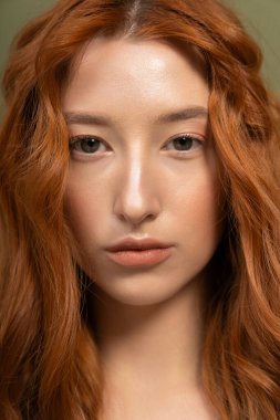 Güzel kızıl saçlı genç bir kadın şık bir stüdyo ortamında bahar modasını sergiliyor..