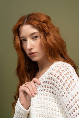 Güzel kızıl saçlı genç bir kadın bahar modası için stüdyoda zarif pozlar veriyor..