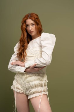 Güzel bir kızıl saçlı kadın, bir stüdyo sahnesinde şık bir bahar elbisesi sergiliyor..