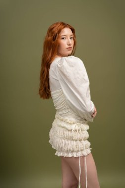 Uçan kızıl saçlı genç kadın moda bahar aylarında şık bir stüdyo ortamında görünüyor..