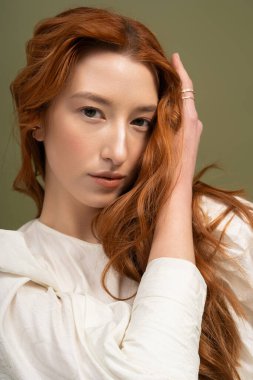 Canlı kızıl saçlı genç bir kadın zarif bir şekilde poz veriyor, bahar modasını gözler önüne seriyor..