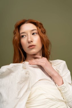 Şık bir bahar elbisesi içindeki güzel genç bir kadın stüdyo ortamında zarifçe poz veriyor..