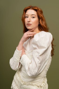 Genç ve güzel bir kızıl saçlı şık bahar modasını sakin bir stüdyoda sergiliyor..