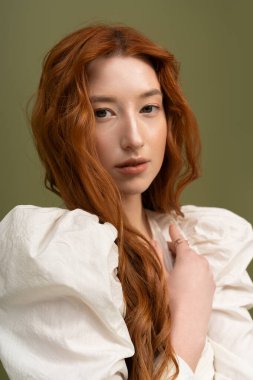 Kendine güvenen genç bir kızıl saçlı model şık bir stüdyoda bahar modasına girdi..