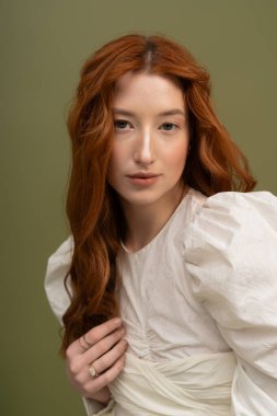 Kızıl saçlı genç bir kadın. Stüdyoda şık bir bahar elbisesi. Zarafet saçıyor..