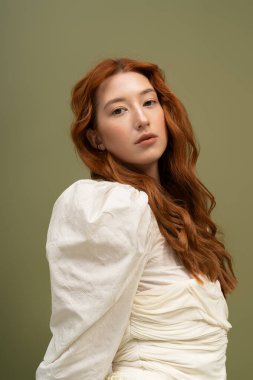 Kızıl saçlı biri şık bir kıyafetle şık bir şekilde poz verir. Huzurlu bir stüdyoda bahar modasını yakalar..