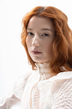 Göz alıcı özellikleri olan genç bir kızıl saçlı stüdyo ortamında şık bahar kıyafetleri sergiliyor..