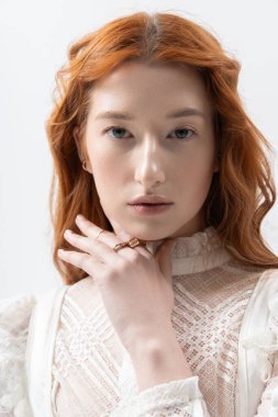 Güzel, kızıl saçlı bir kadın şık bir elbiseyle poz veriyor, bahar havasını uyandırıyor..