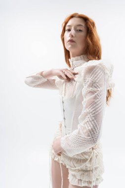 Çarpıcı kızıl saçlı genç bir kadın zarif poz veriyor, modern bahar moda eğilimlerini somutlaştırıyor.