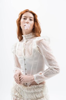 Güzel genç bir kızıl zarif bir şekilde bahar modasına uygun poz veriyor ve büyüleyici bir sahne yaratıyor..