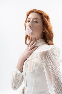 Kızıl saçlı genç kadın bir stüdyoda poz veriyor, baharın özünü yakalıyor..