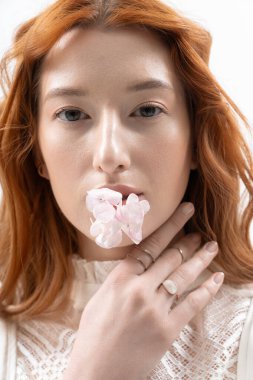 Genç kızıl saçlı bir kadın zarif bir şekilde poz veriyor. Etrafı bahar havalarıyla çevrili..