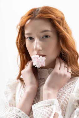 Genç kızıl saçlı bir kadın zarif bir şekilde poz veriyor. Stüdyoda. Bahar modasını ve güzelliğini temsil ediyor..