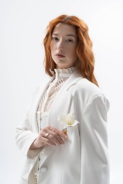 Güzel bir kızıl şık bir şekilde poz veriyor. Stüdyoda bahar atmosferi sergiliyor..