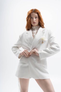 Kızıl saçlı güzel bir kadın stüdyo ortamında şık bahar kıyafetleri sergiliyor..