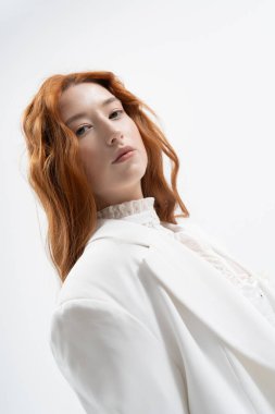 Genç, kızıl saçlı bir kadın kendine güvenerek poz veriyor. Şık bir bahar elbisesi, gençlik ve güzellik saçıyor..